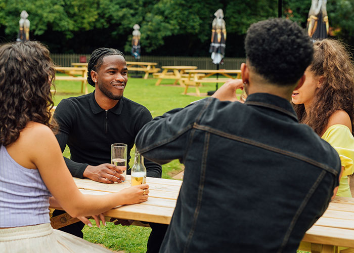 Friends eating and drinking together at Toby Carvery Worcester Park restaurant with outdoor seating